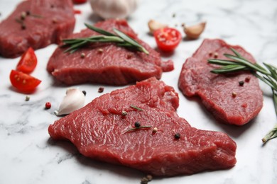 Photo of Fresh raw meat steaks and spices on white marble table, closeup