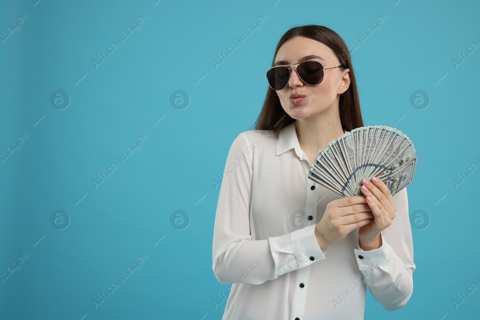 Photo of Woman with dollar banknotes on light blue background, space for text