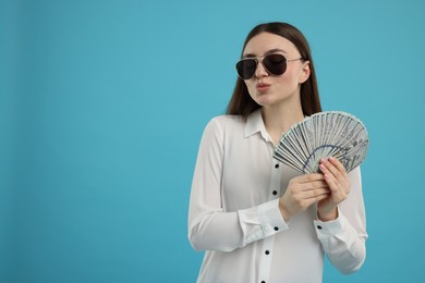 Woman with dollar banknotes on light blue background, space for text