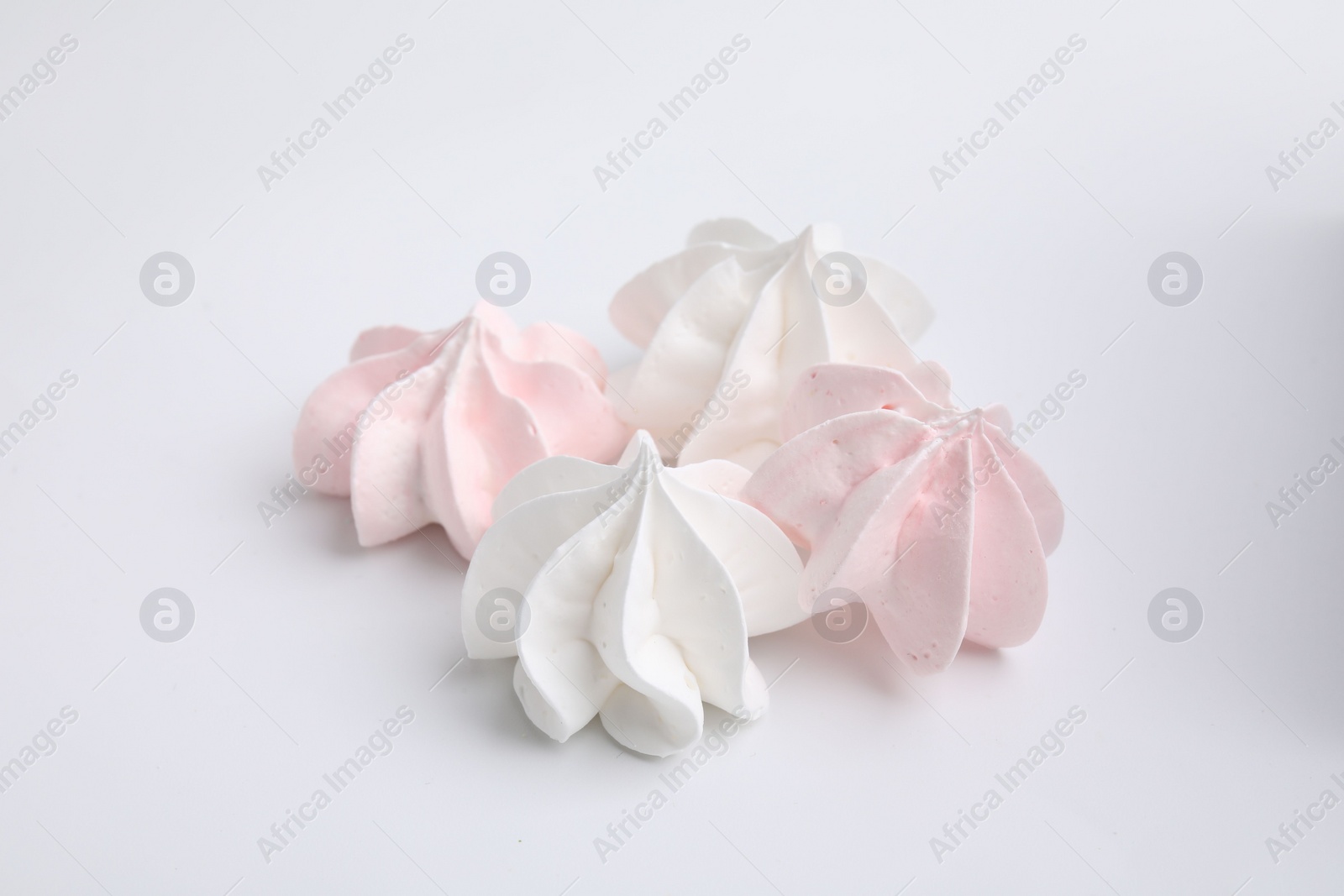 Photo of Many delicious meringue cookies isolated on white