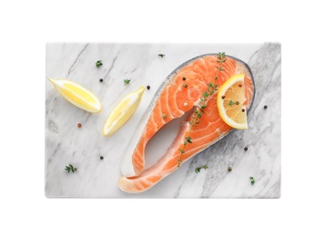 Photo of Marble board with fresh salmon steak and lemon on white background, top view