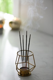 Photo of Incense sticks smoldering on table in room