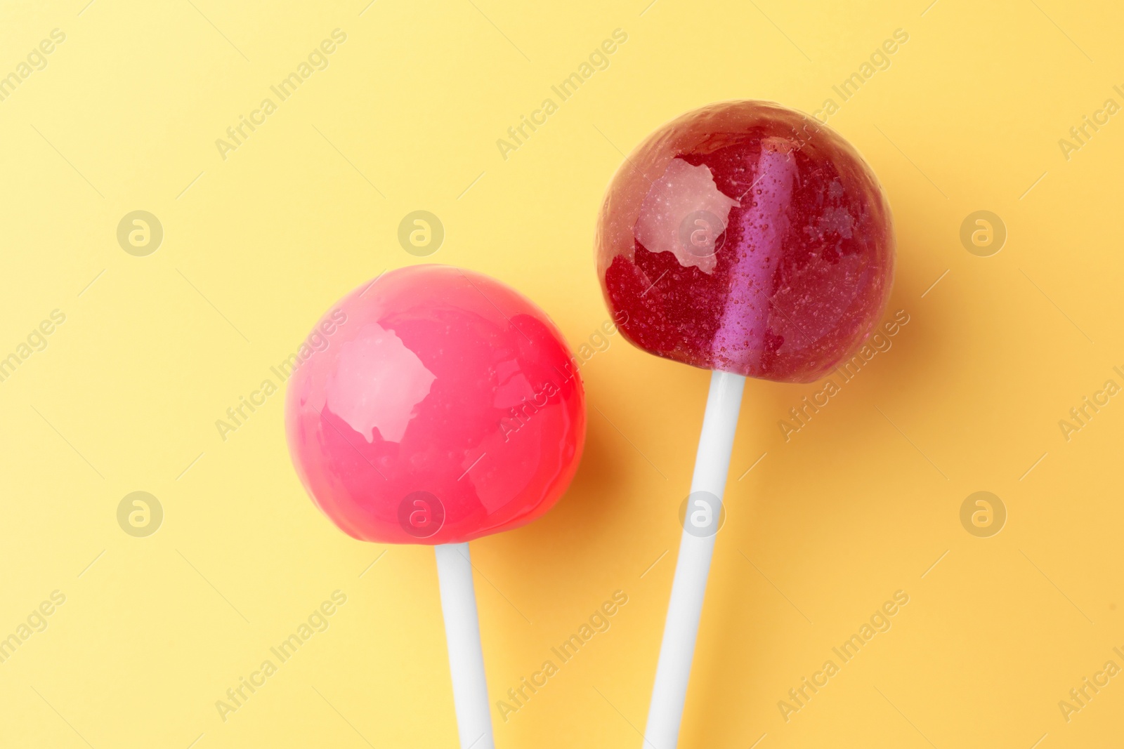 Photo of Tasty lollipops on yellow background, flat lay