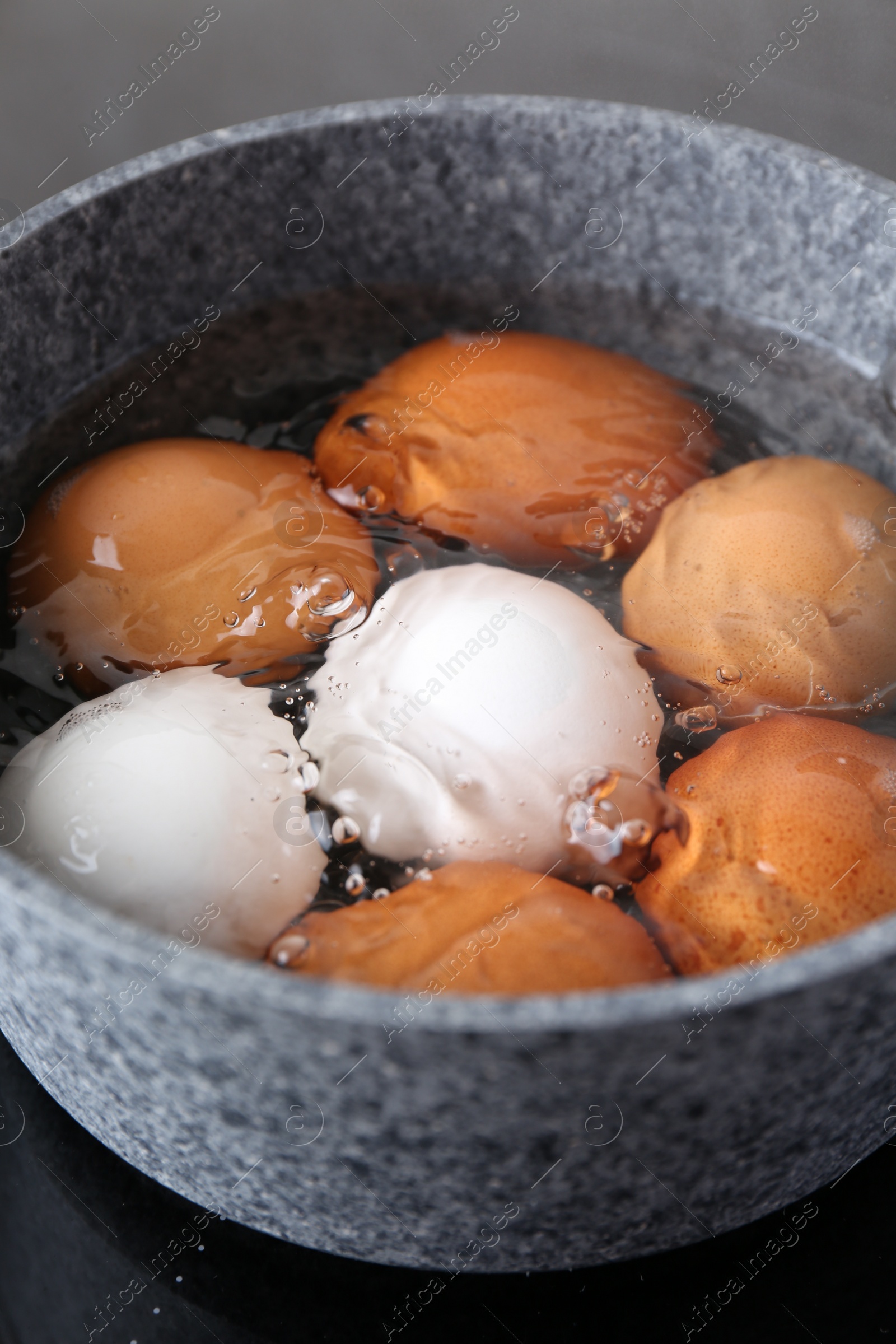 Photo of Chicken eggs boiling in saucepan on electric stove, closeup