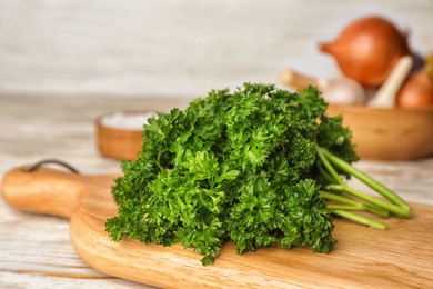 Wooden board with fresh curly parsley on table