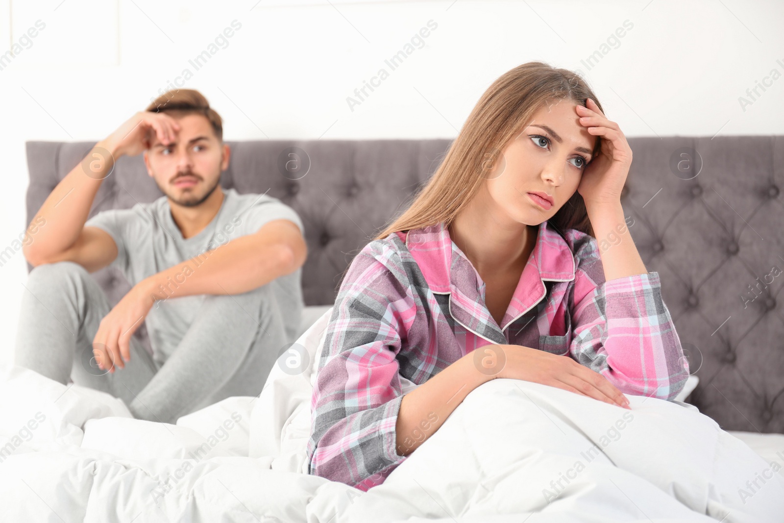 Photo of Young couple with relationship problems ignoring each other in bedroom