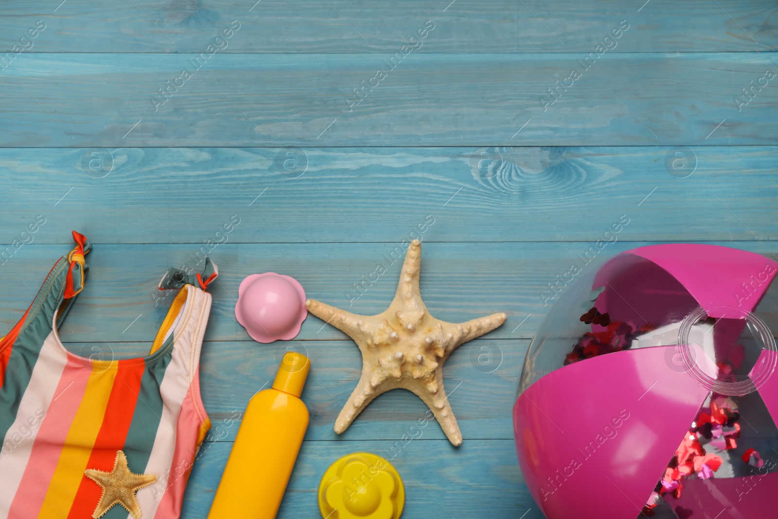 Photo of Flat lay composition with beach ball on light blue wooden background. Space for text