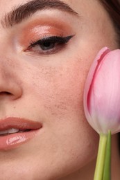 Beautiful woman with fake freckles and tulip, closeup