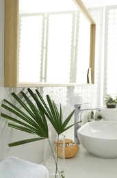 Photo of Tropical palm leaves in stylish bathroom interior