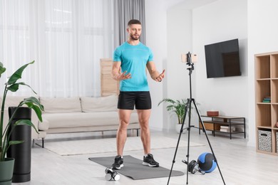 Photo of Trainer streaming online fitness lesson with phone at home