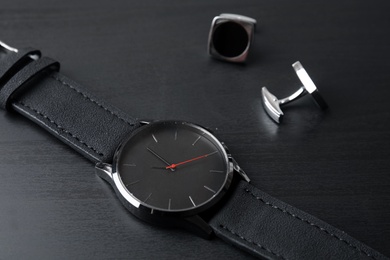 Photo of Stylish wrist watch and cuff links on dark table. Fashion accessory