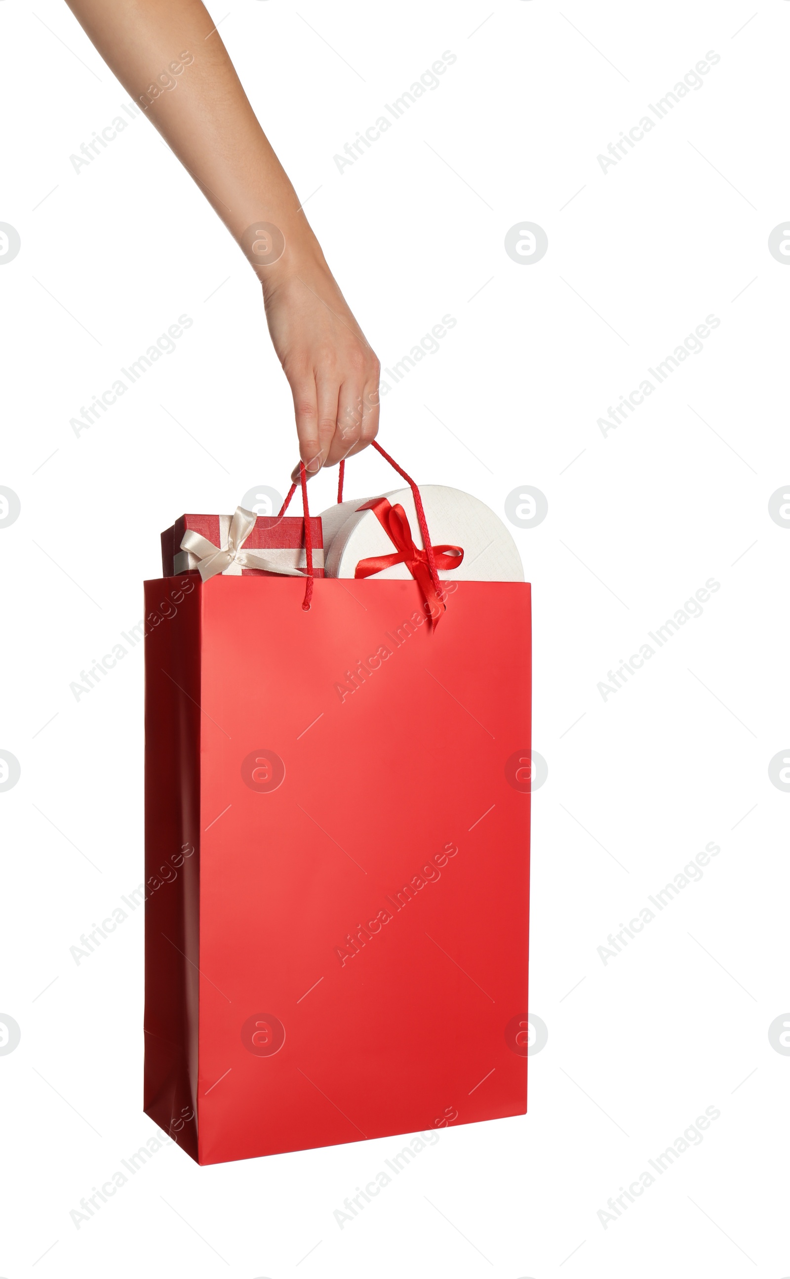 Photo of Woman holding paper shopping bag full of gift boxes on white background, closeup