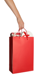 Photo of Woman holding paper shopping bag full of gift boxes on white background, closeup