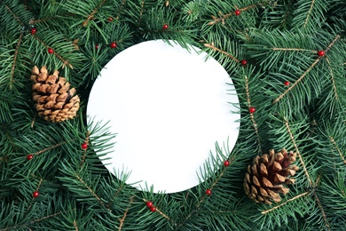 Photo of Blank card and pine cones on Christmas tree branches as background, flat lay. Space for text