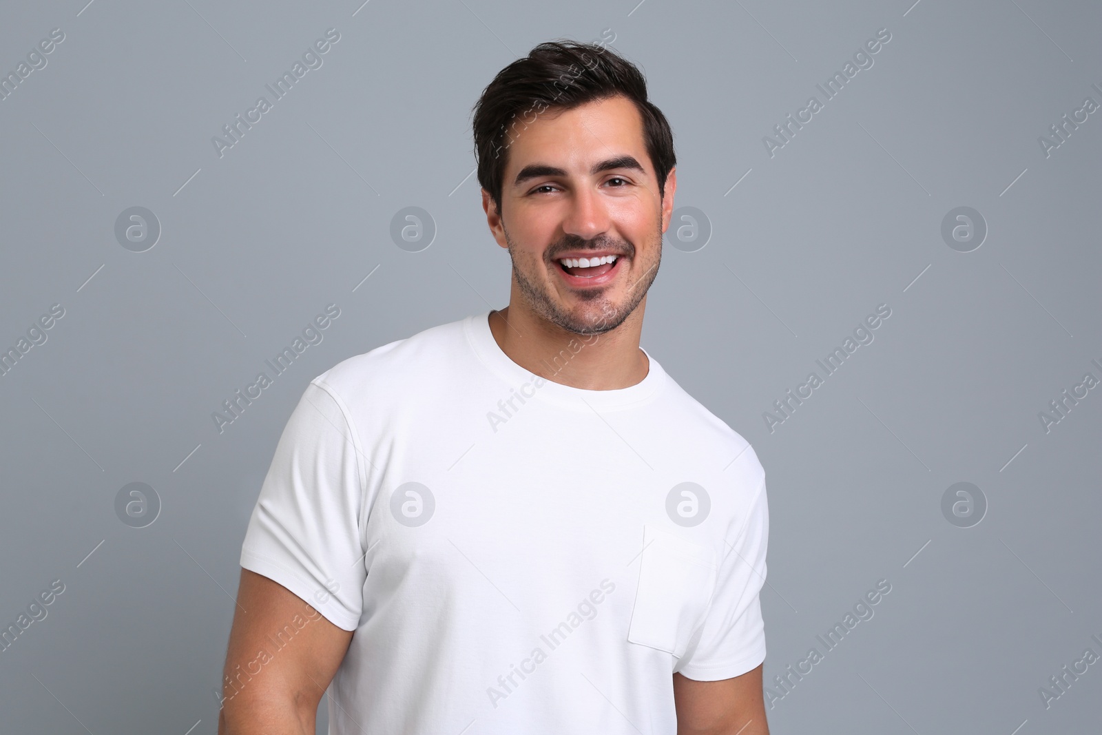 Photo of Portrait of handsome young man in white t-shirt on grey background