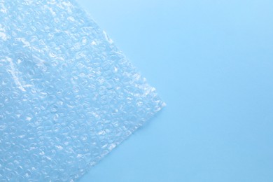 Photo of Transparent bubble wrap on light blue background, top view. Space for text