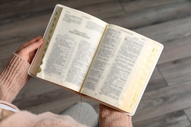 Photo of Above view of woman reading Bible indoors, closeup