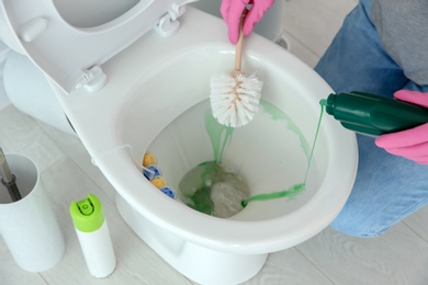 Woman cleaning toilet bowl in bathroom