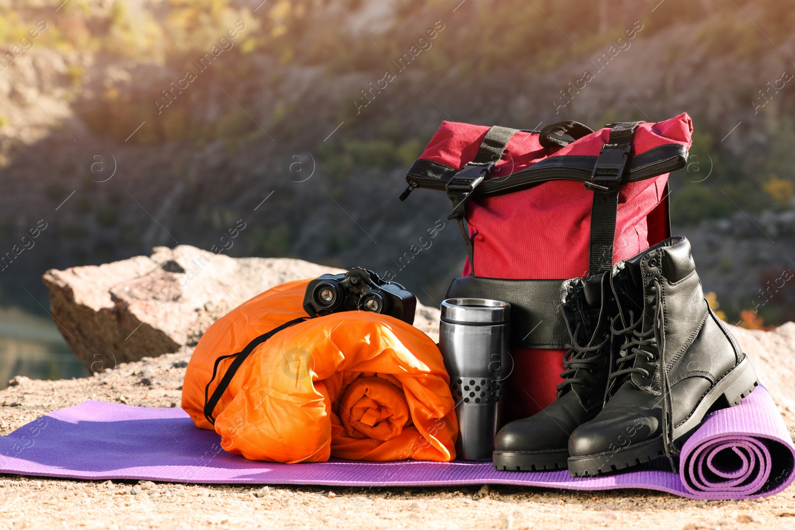 Photo of Set of camping equipment with sleeping bag on ground outdoors