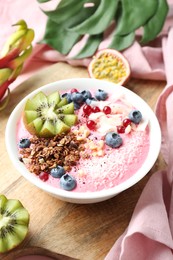 Photo of Tasty smoothie bowl with fresh kiwi fruit, berries and granola on pink table