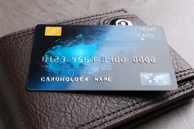 Credit card and leather wallet on grey table, closeup