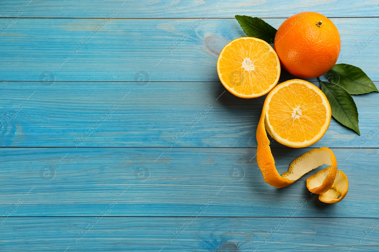 Photo of Orange fruits with peel on light blue wooden table, flat lay. Space for text