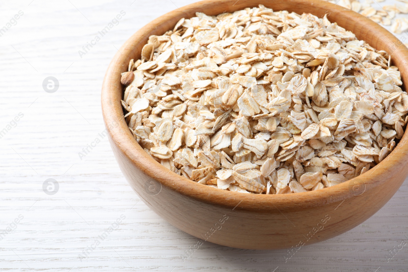 Photo of Bowl with oatmeal on white wooden table