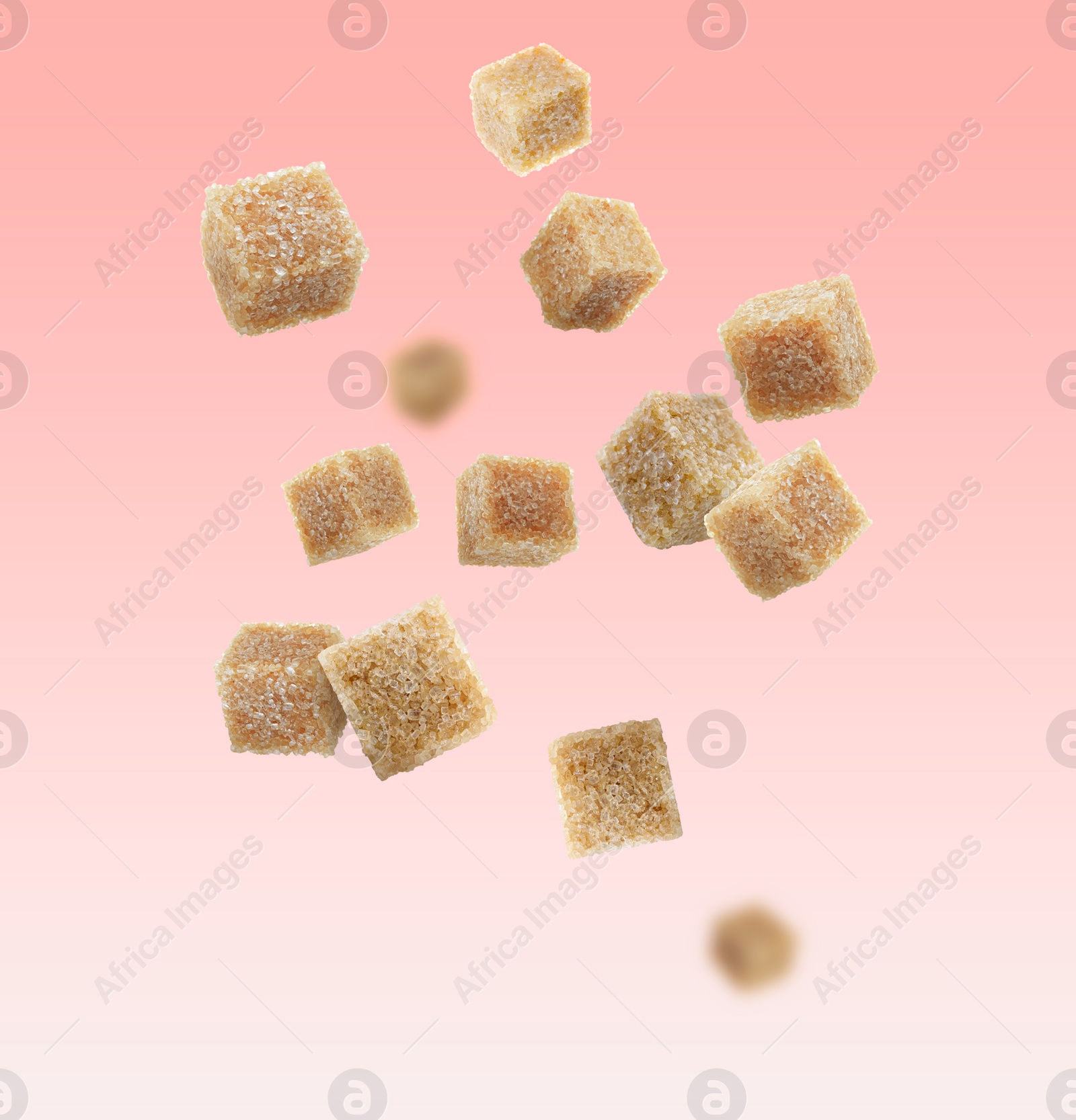 Image of Brown cane sugar cubes falling on pink gradient background