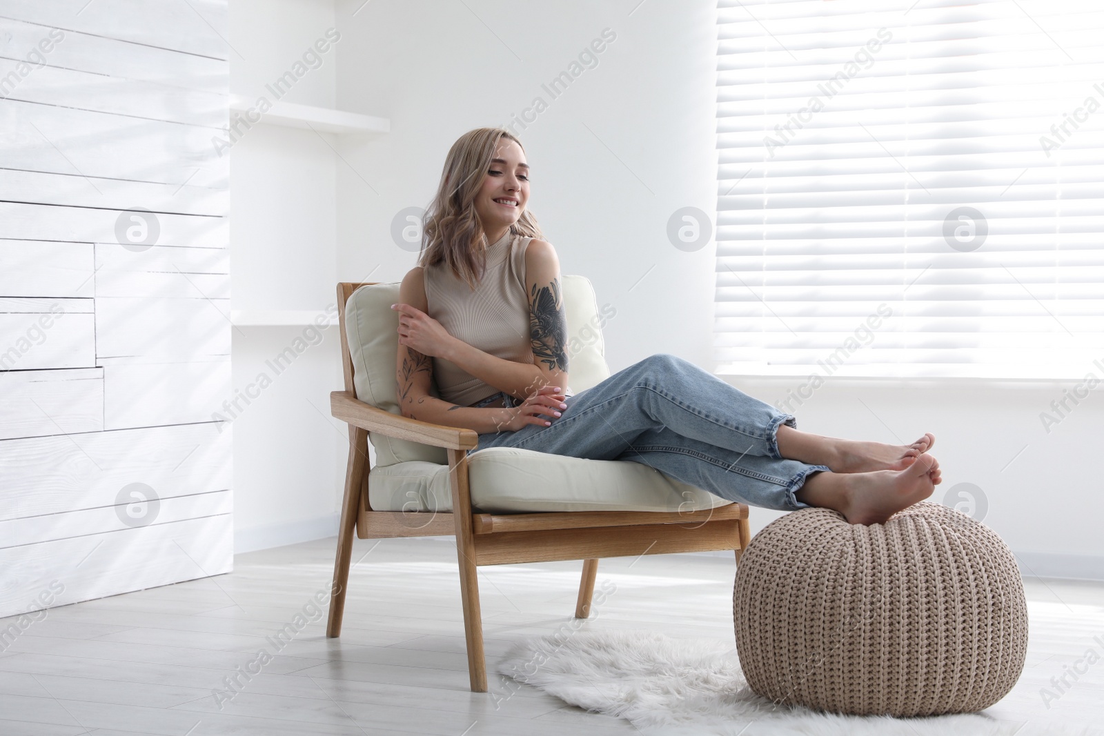 Photo of Beautiful woman with tattoos on arms resting at home