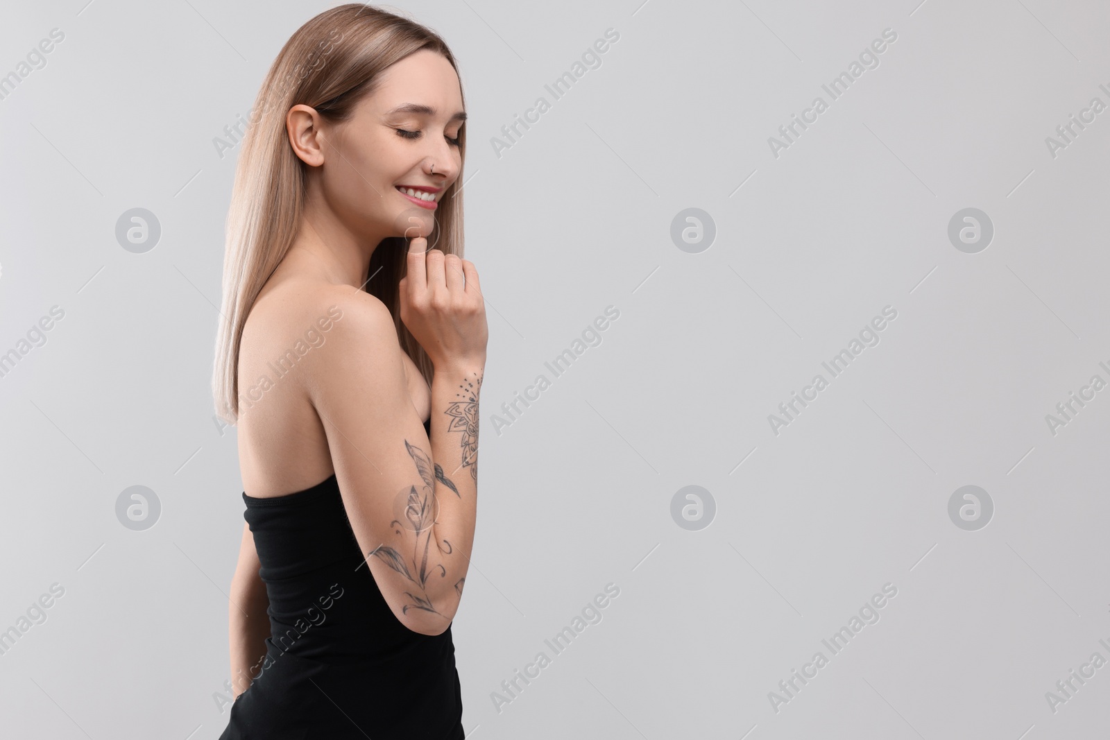 Photo of Portrait of beautiful tattooed woman on light background, space for text
