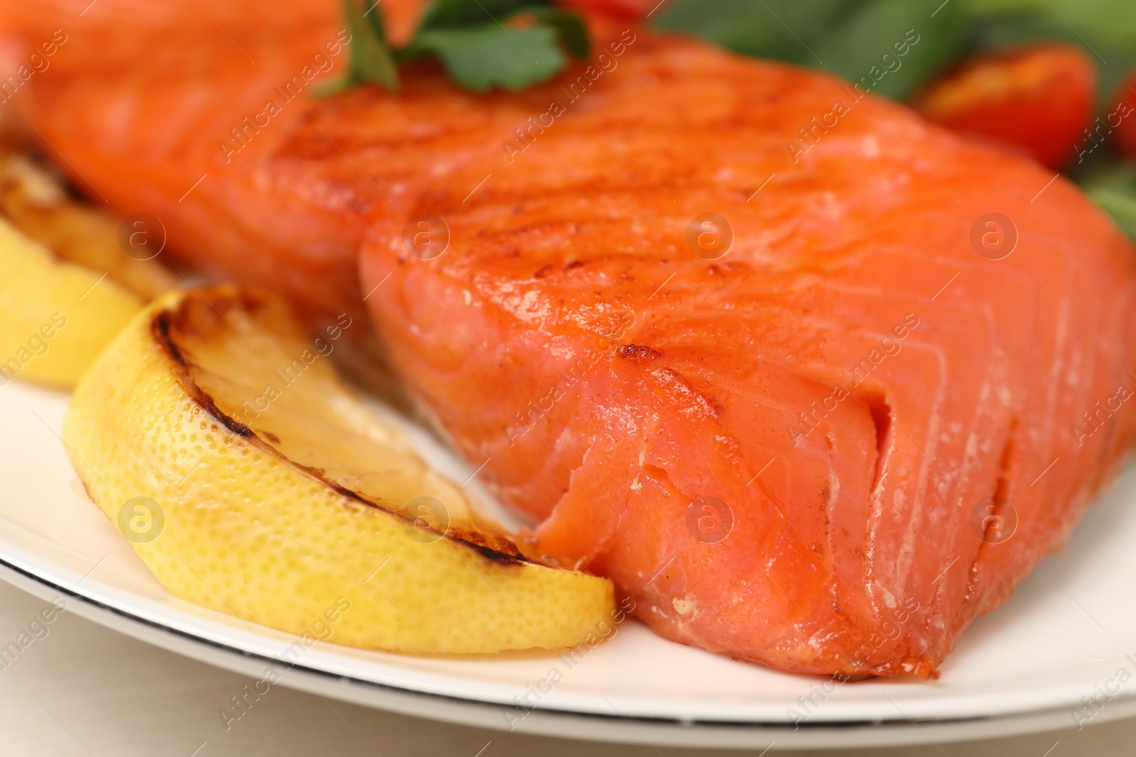 Photo of Tasty grilled salmon with lemon on white table, closeup