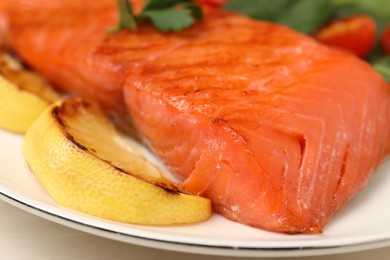 Photo of Tasty grilled salmon with lemon on white table, closeup