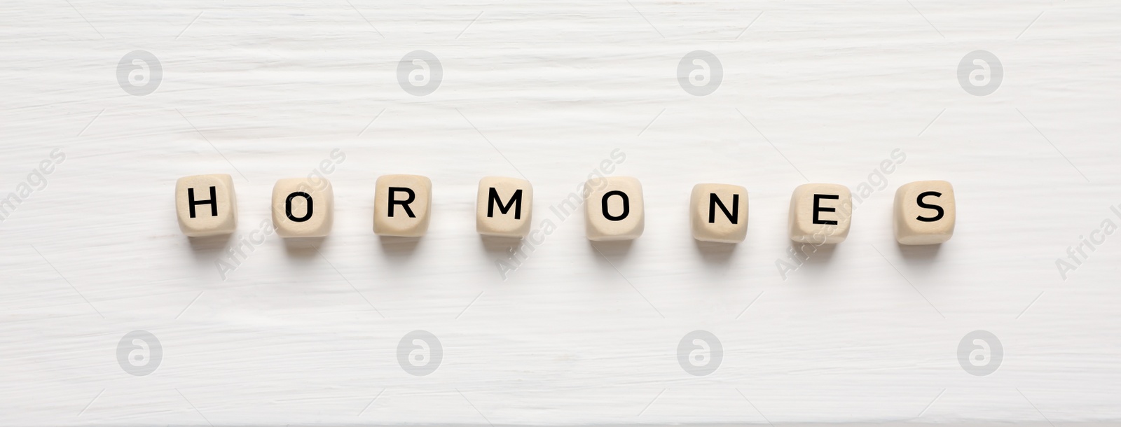 Photo of Word HORMONES made with wooden cubes on white table, flat lay. Space for text