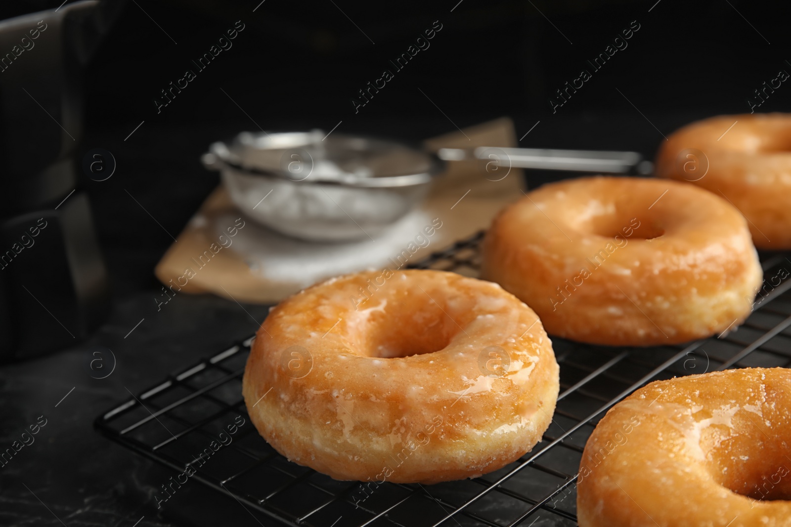 Photo of Sweet delicious glazed donuts on black table