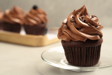 Photo of Delicious chocolate cupcake with cream and crumbles on light grey table, closeup. Space for text