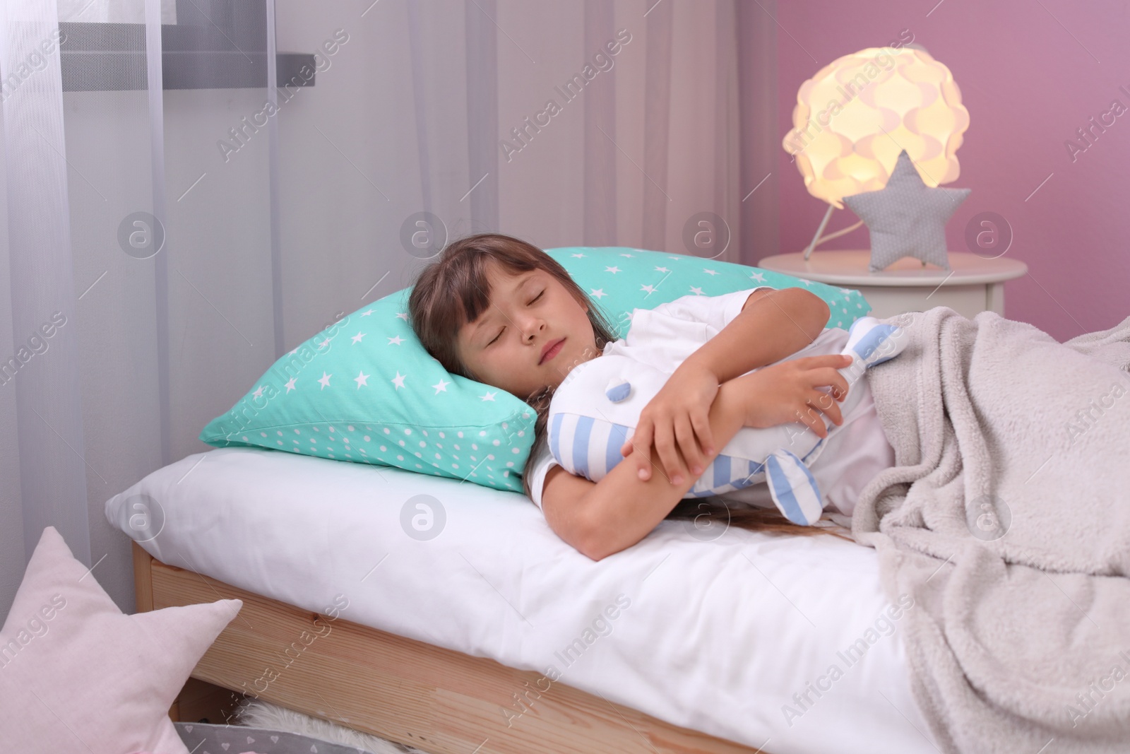 Photo of Little girl with toy sleeping in bed at home