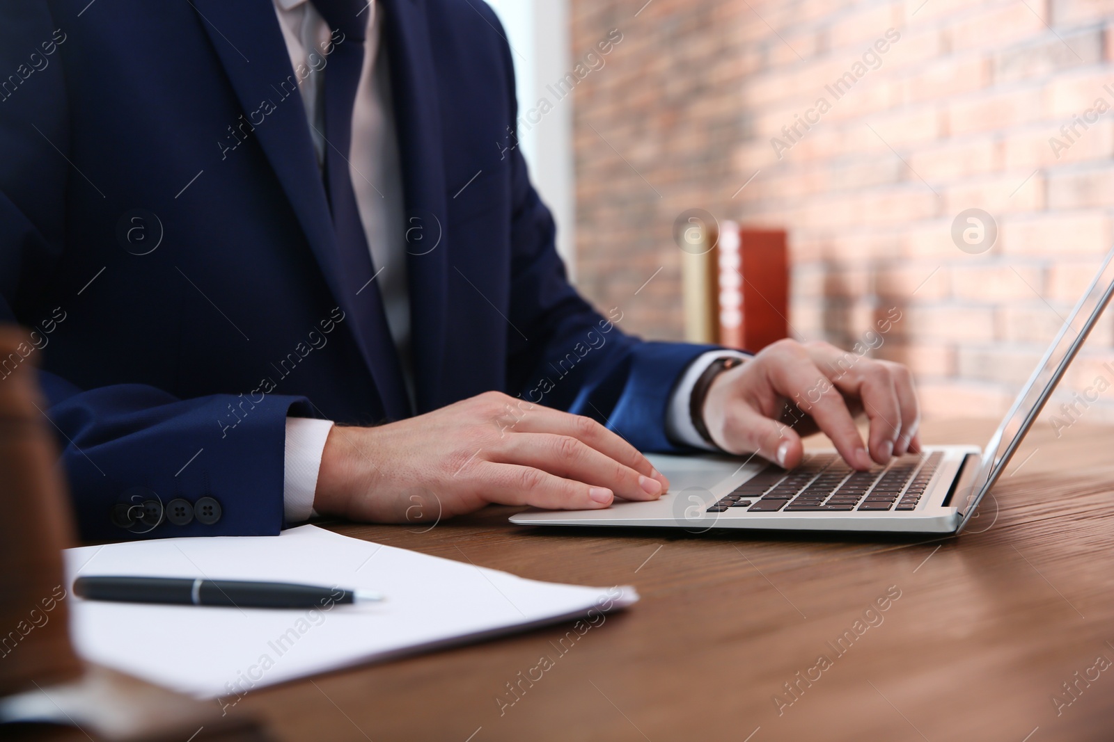 Photo of Notary working with laptop at table in office, closeup. Law and justice concept