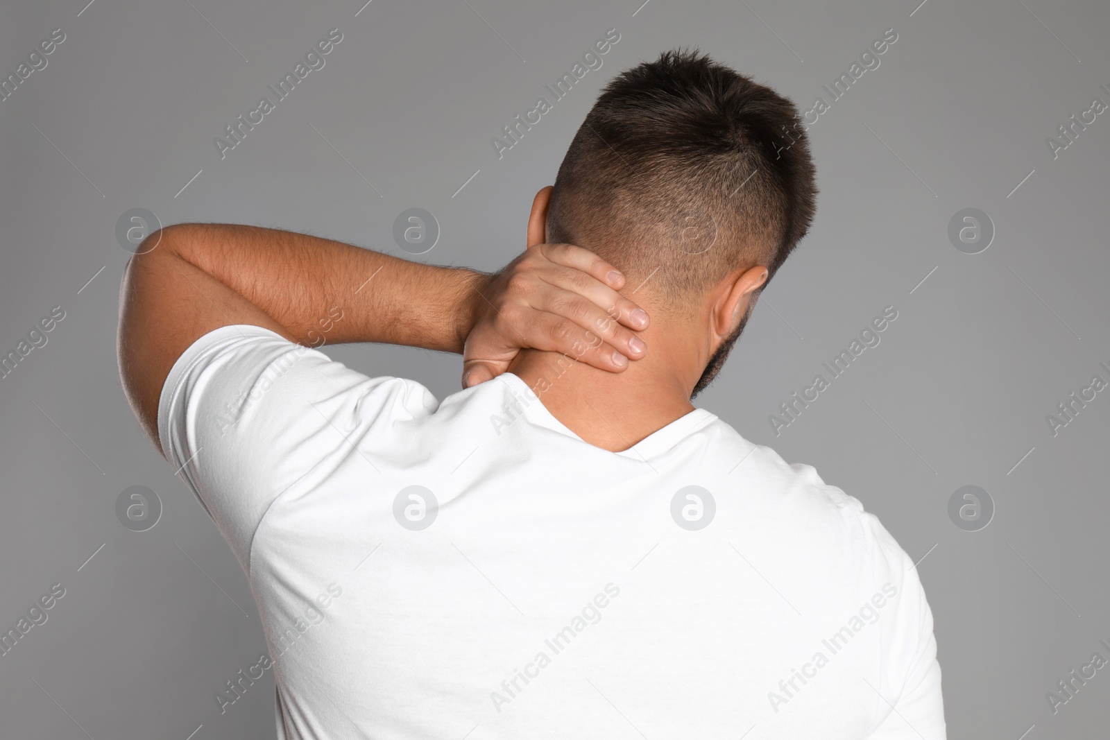 Photo of Man suffering from neck pain on light grey background