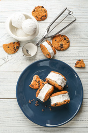 Sweet delicious ice cream cookie sandwiches served on white wooden table, flat lay