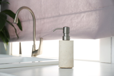 Photo of Modern soap dispenser near sink in kitchen