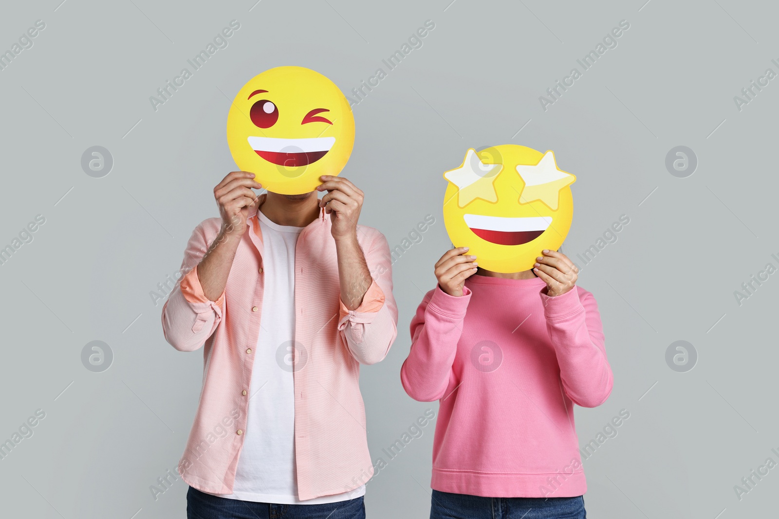 Photo of People covering faces with happy emoticons on grey background