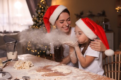 Mother with her cute little daughter having fun while making dough for Christmas cookies in kitchen