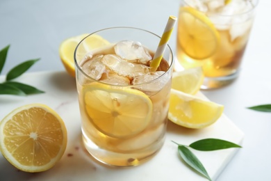 Glass of lemonade with ice cubes and fruit on table