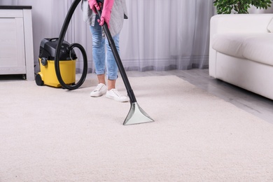 Woman cleaning carpet with vacuum cleaner, closeup