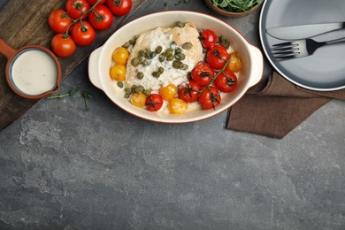 Photo of Delicious baked chicken fillet with capers, sauce and tomatoes in baking dish on grey table, flat lay. Space for text