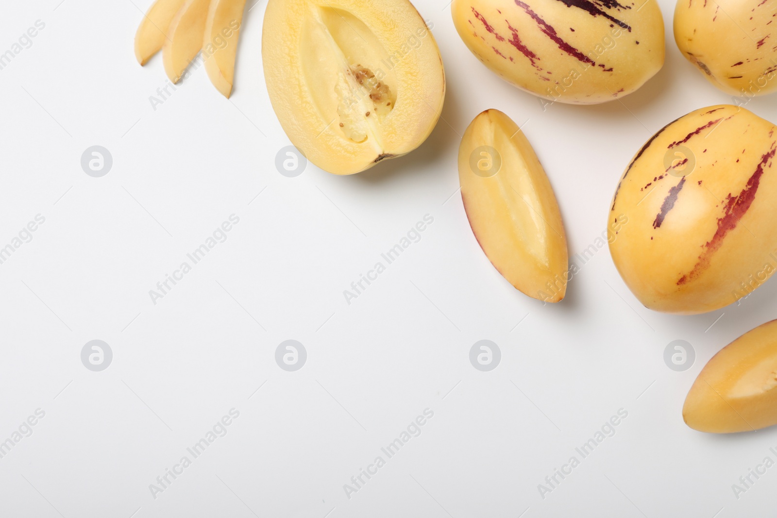 Photo of Whole and cut pepino melons on white background, flat lay. Space for text