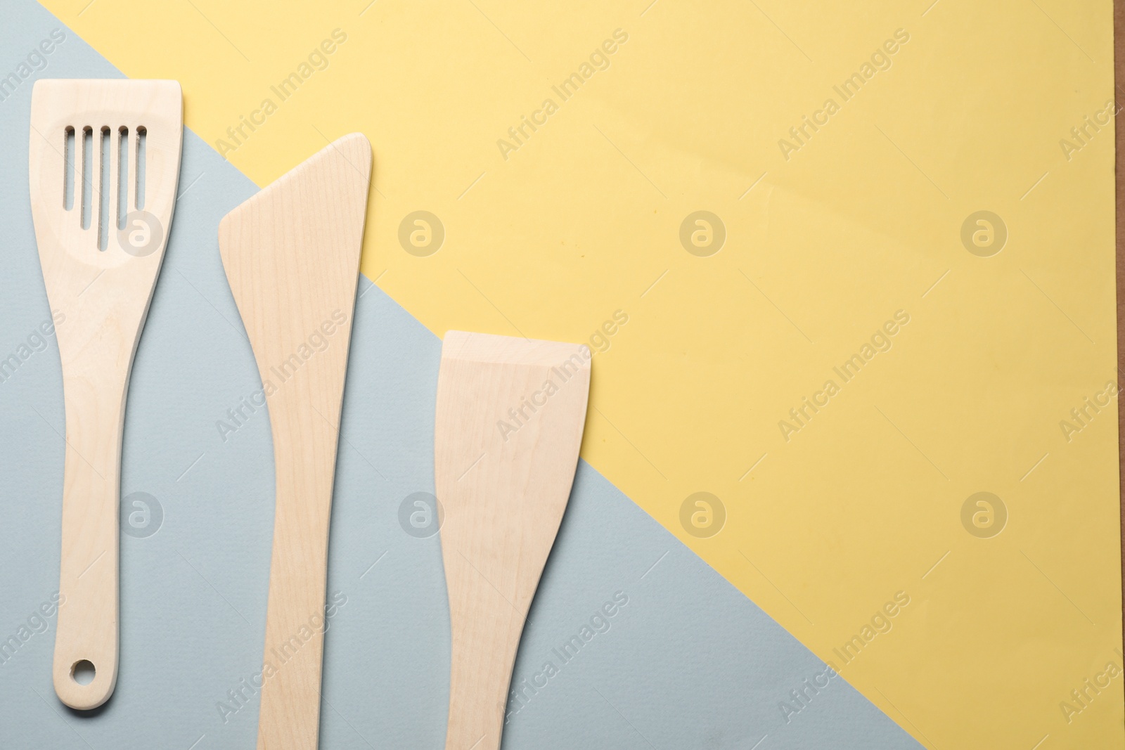 Photo of Different wooden spatulas on color background, flat lay. Space for text