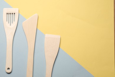 Photo of Different wooden spatulas on color background, flat lay. Space for text