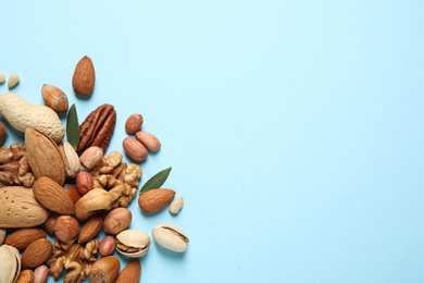 Different delicious nuts on light blue background, flat lay. Space for text