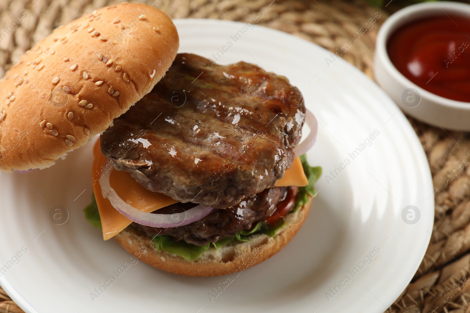 Photo of Tasty hamburger with patties, cheese and vegetables on wicker mat, closeup